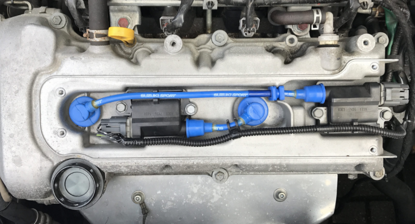 closeup of engine cover which show blue suzuki sport plug leads
