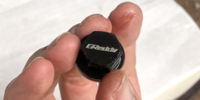 Hand holding a used greddy oil drain plug